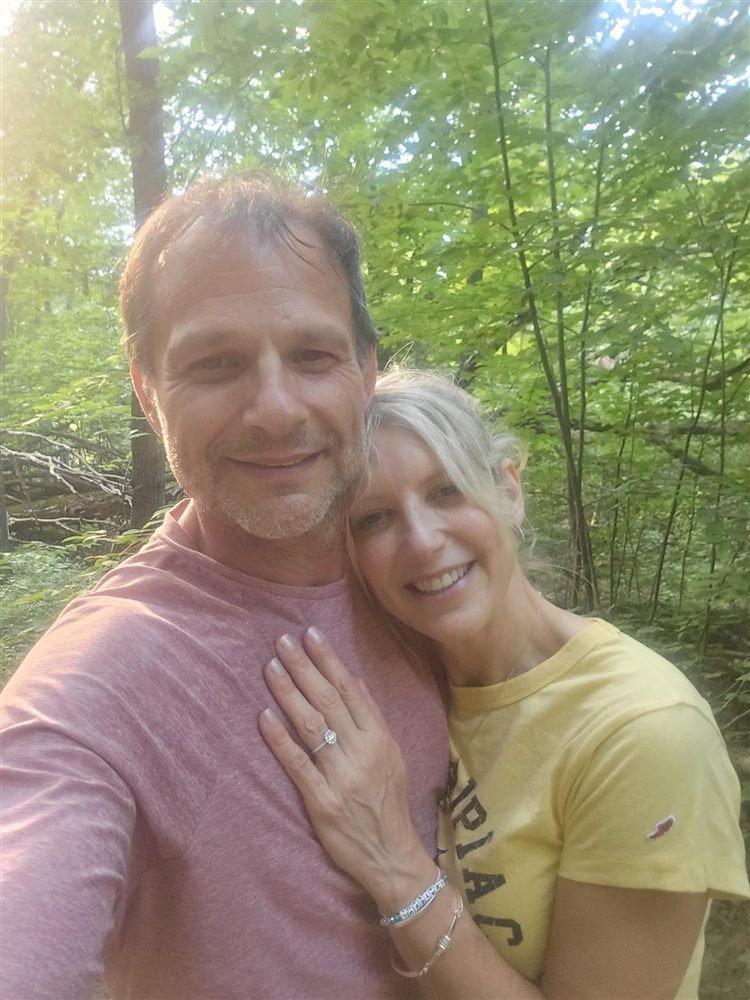 Bethany and Jeff in the woods with her engagement ring on his chest